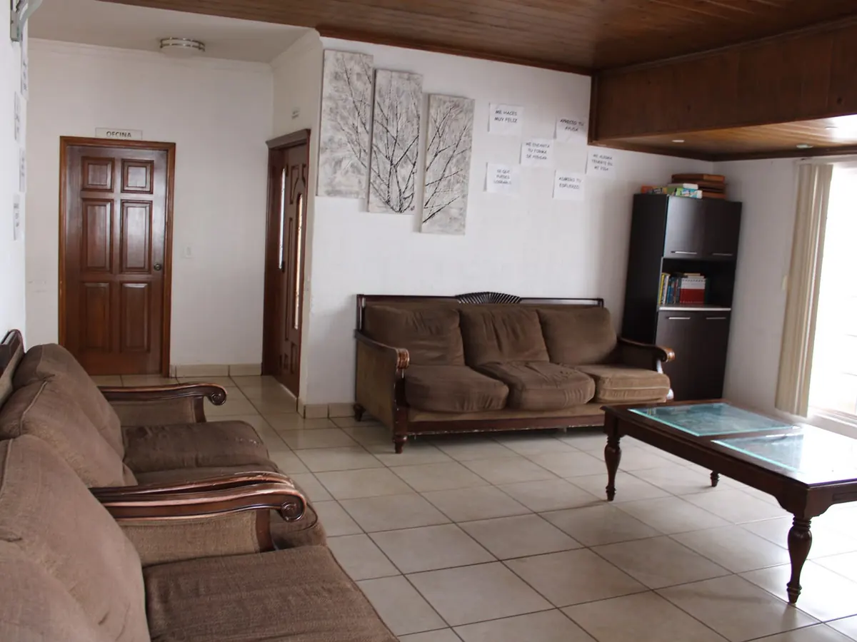 Sala común de Despertares con sillones, librero y una pared de notas escritas a mano por los residentes.
