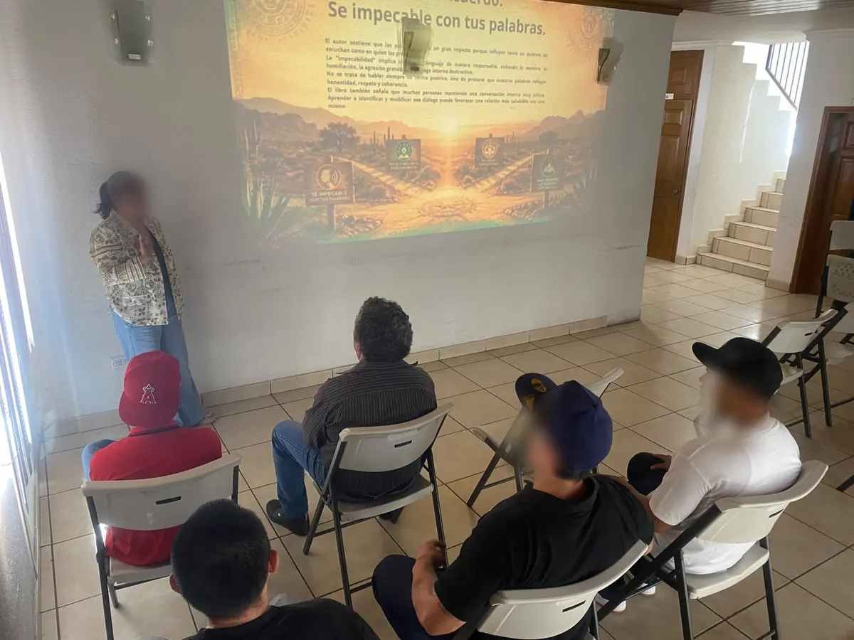 A group session at Despertares: a psychologist presents a slide while five residents listen, seated in a semicircle.