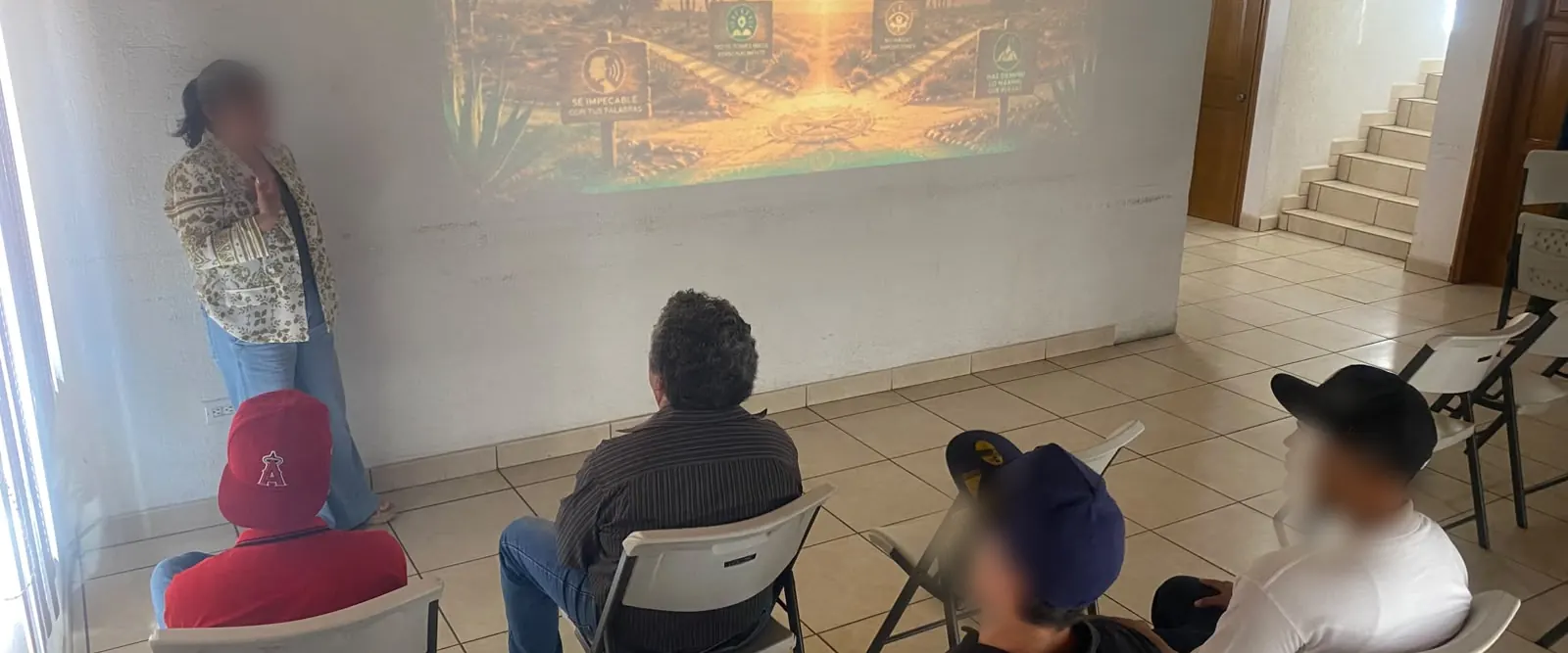 Sesión de grupo en Despertares: una psicóloga presenta una lámina mientras cinco residentes escuchan sentados en semicírculo.